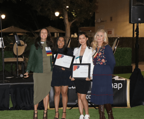 Four ladies at an awards event, 2 receiving a certificate.