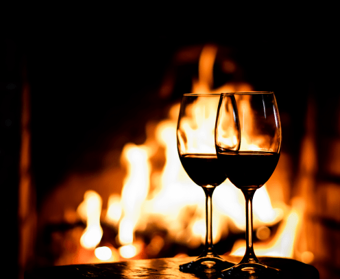 Two glasses of red wine on the background of fireplace lights. Christmas holiday concept