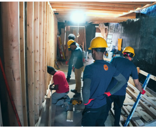 construction workers on a job site framing a wall with plywood