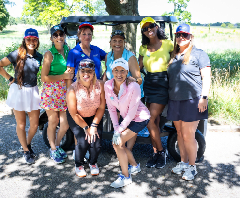 diverse ladies at a golf course standing in front of a golf cart