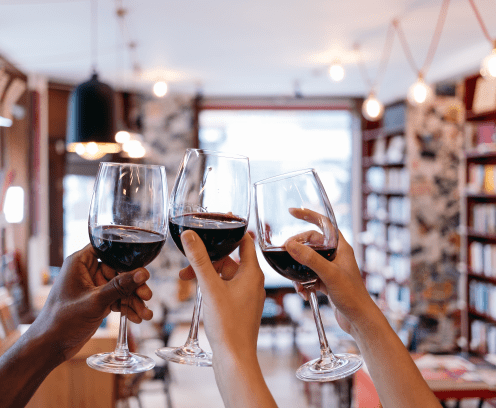 toasting raised hands holding glasses in a book cafe - celebration
