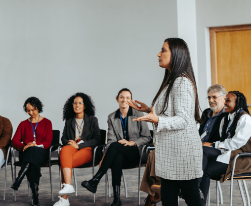 A female instructor engaging with a diverse team in a teambuilding session at a modern office, fostering collaboration and teamwork.