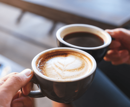 two-specialty-coffee-drinks-in-mugs-in-hands-in-toast-mode