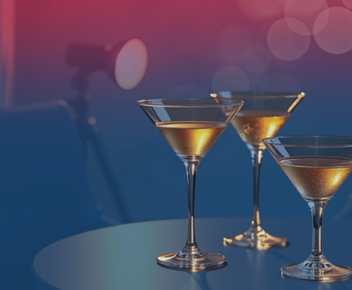 Three martini glasses on a table next to a spot light