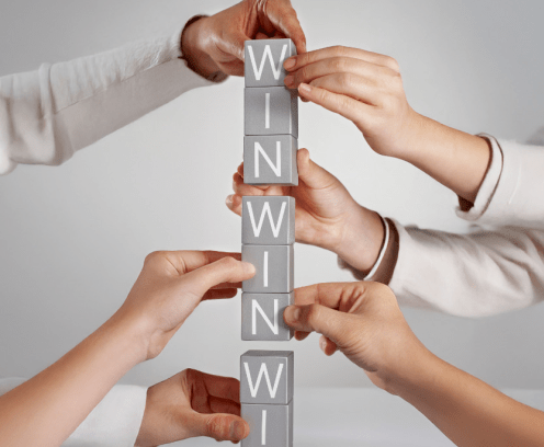 Many hands holding blocks that spell win win win