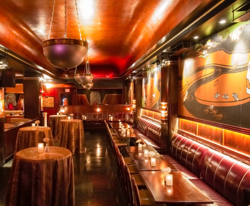 Low lit room with booths and cocktail tables.