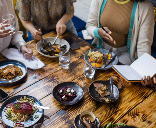 women gathered around a table of plates with different types of dishes