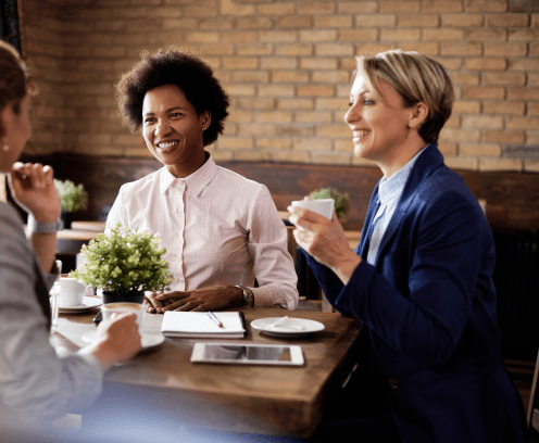 Happy black business woman talking to her colleagues at a cafe.