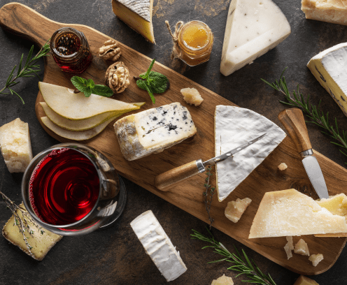 Wooden cheese board with glass of red wine, jam and honey jars.