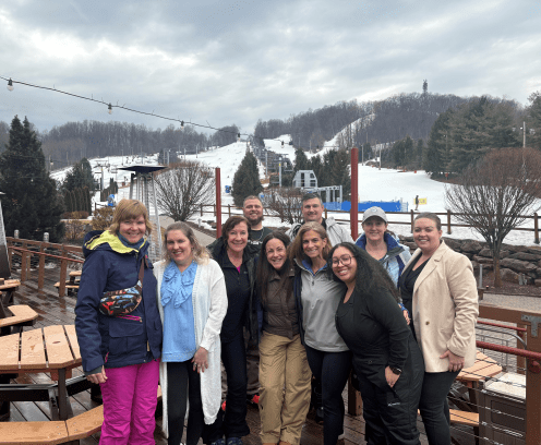 Group of people at ski day 2025, ski lift in background.
