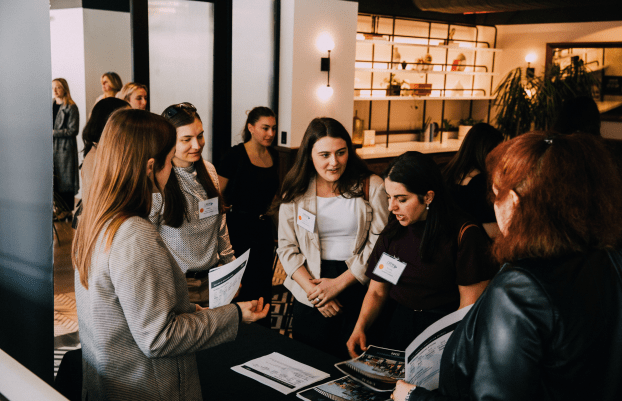 Women networking at registration table, entering event.