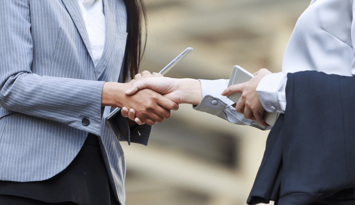 business women shaking hands with iphone and tablets in their hands
