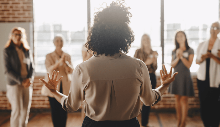 Businesswoman with arms outstretched talking to a small group