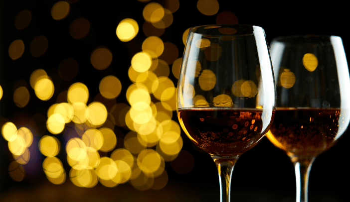 Two glasses of sparkling wine or champagne to celebrate New Year, Merry Christmas or Anniversary with a bokeh effect background. The yellow of the wine and lights stand out against a dark background.