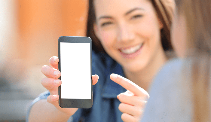 Woman showing a blank smart phone screen to a friend