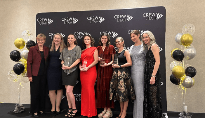 Eight ladies standing in front of CREW Utah banner at Gala event