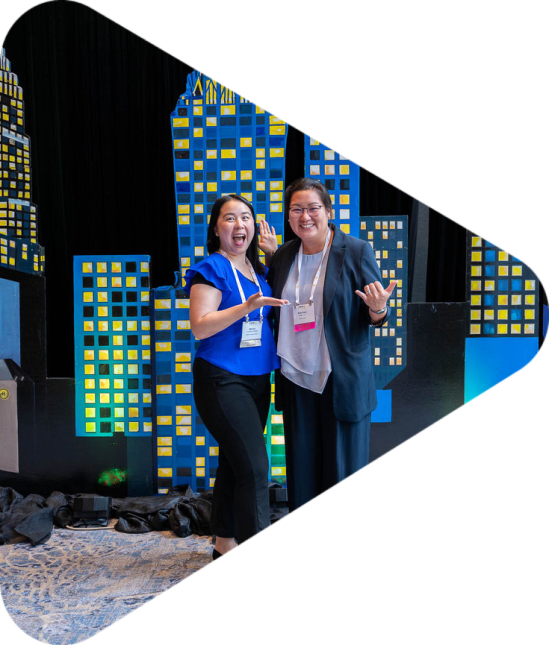 Two women posing in front of a CREW Charlotte city back drop