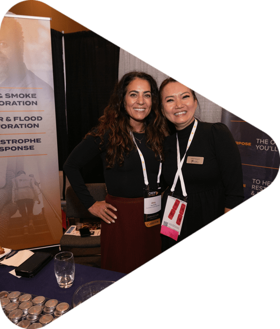Two women posing at an exhibitors booth