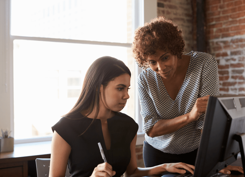 Two Businesswomen Working On Computer In Office mentor concept