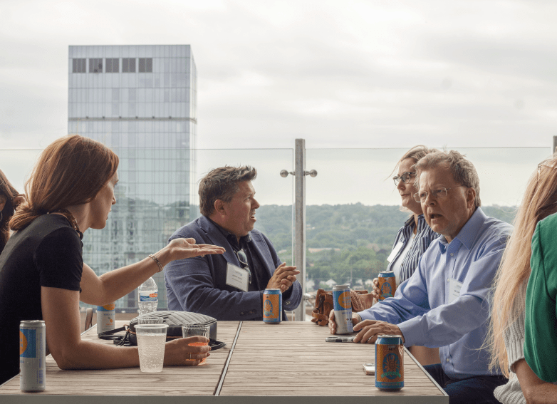 people networking at a table on a rooftop bar