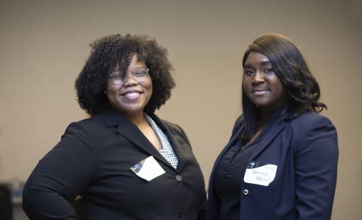 two women smiling at camera with name tags on at a crew event