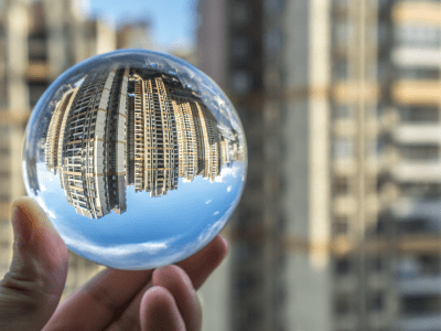hand holding a glass ball reflecting city buildings in the background
