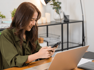 Asian business woman using laptop checking smartphone indoors home office, Happy female smile working multiple devices with computer and mobile phone, beautiful people pay digital online on desk