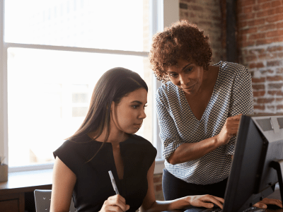 Two Businesswomen Working On Computer In Office mentor concept