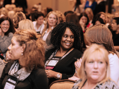woman sitting in audience smiling at another woman