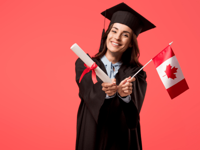 smiling female student in academic gown holding canadian flag isolated on living coral