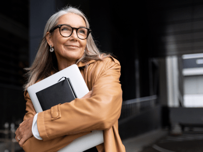 portrait of an elderly businesswoman with a laptop in glasses outside the office.