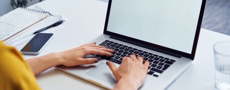 Closeup of woman using laptop with white blank screen mockup