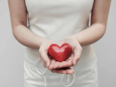 woman offering a red heart-shaped stone to camera