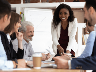 Different ethnicity and age businesspeople gathered together at boardroom for negotiations and planning future collaboration lead by african smiling businesswoman or corporate training process concept