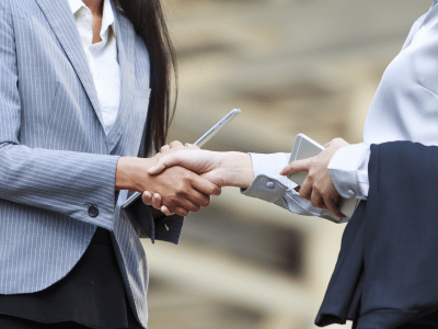 business women shaking hands with iphone and tablets in their hands