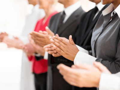 group of businesspeople clapping hands during meeting presentation