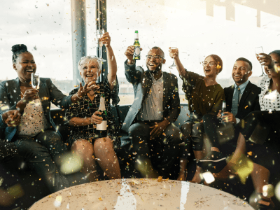 A festive multi ethnic group of people smiling, toasting with sparkling wine and beer. Celebrating the end of the working year and to the new year ahead