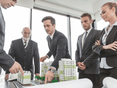 Business meeting of architects and investors looking at model of residential quarter houses