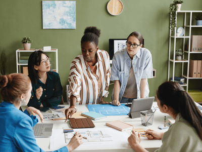 African architect presenting construction project to her colleagues at table during teamwork at office