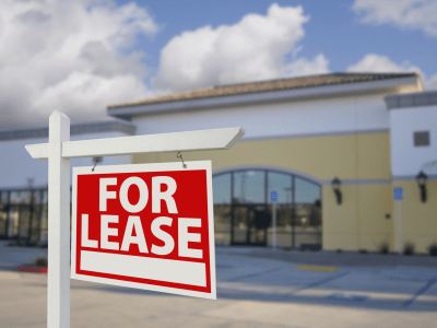 Vacant Retail Building with For Lease Real Estate Sign in Front.