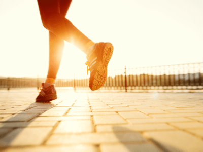 Runner feet running on road closeup on shoe. woman fitness sunrise jog workout welness concept.