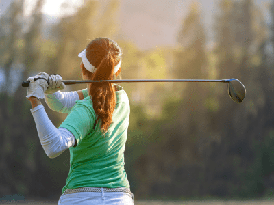 Sport Healthy. Asian sporty woman golf player doing golf swing tee off on the green sunset evening time, she presumably does exercise. Healthy and Lifestyle Concept.