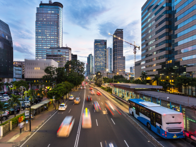 Traffic rushes in Jakarta business district along the city main avenue Jalan Thamrin at sunset in Indonesia capital city. The Transjakarta bus system enjoys its own traffic lane to avoid congestion.