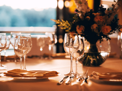 round table with a white tablecloth. the table is decorated with a vase of flowers. wine glass and champagne glass.