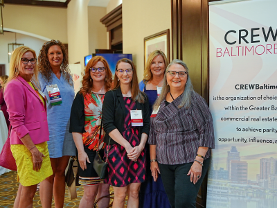 CREWBaltimore members in a conference hall next to a CREWBaltimore sign