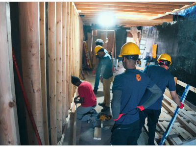 construction workers on a job site framing a wall with plywood