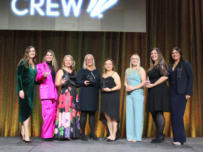 Women Standing on Stage with glass Awards.