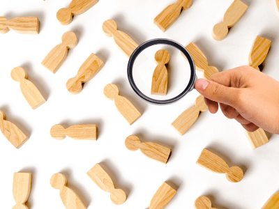 Magnifying glass is looking at the lot of people figures on a white background. The concept of finding and choosing new employees, market research and consumer preferences. recruitment management.