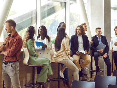 Diverse business professionals communicating at a conference, seminar or other educational event. Young and mature multiethnic people meeting in the office and having discussions. Banner background