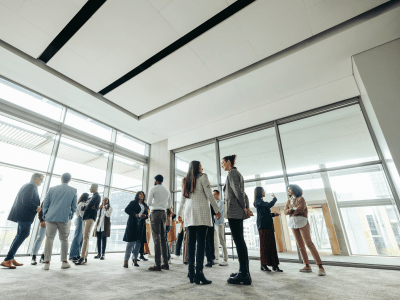 Businesspeople attending a corporate event, networking and engaging in discussions in a large, modern, bright office space.